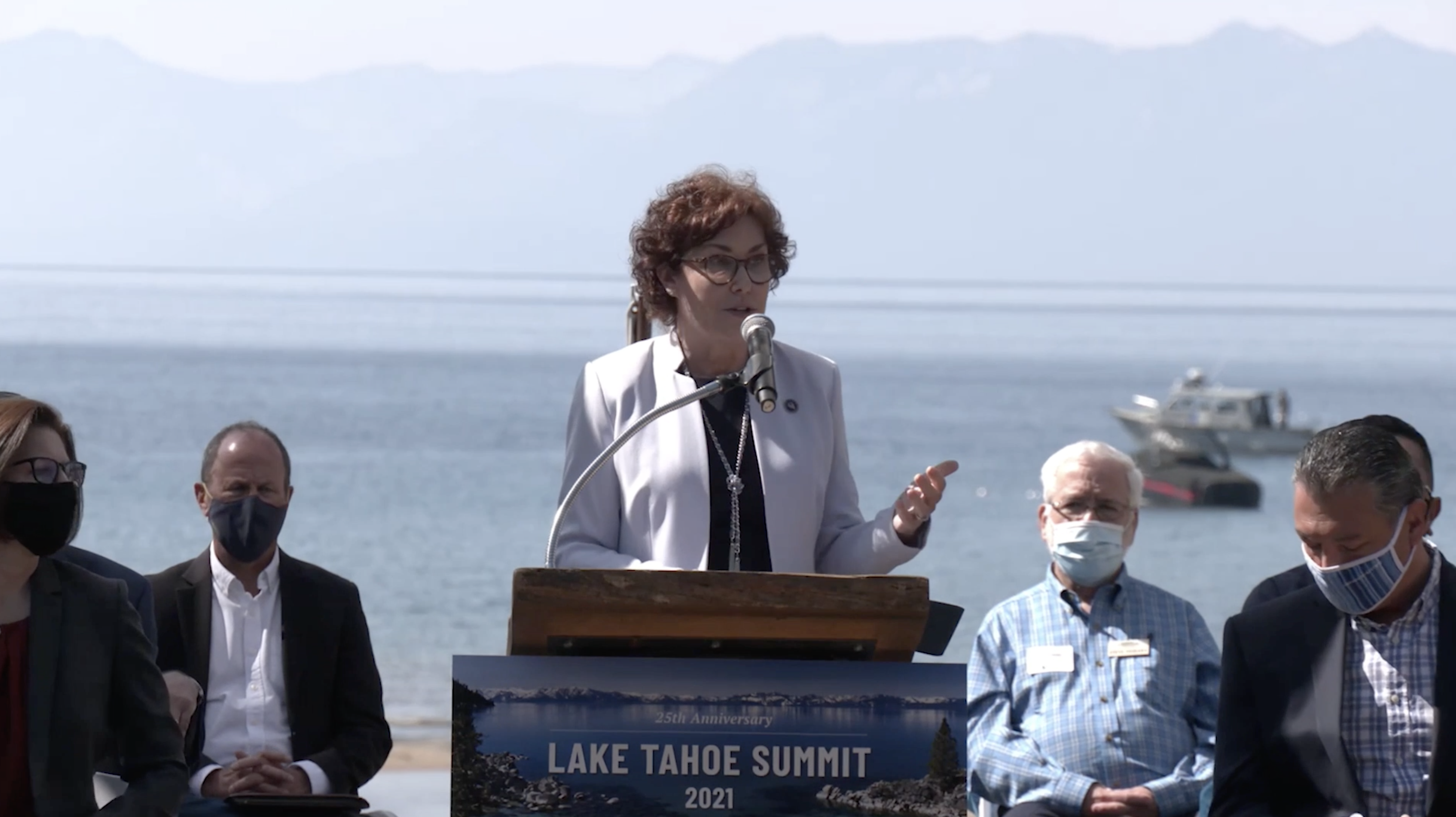 Senator Rosen standing at a podium with Lake Tahoe behind her